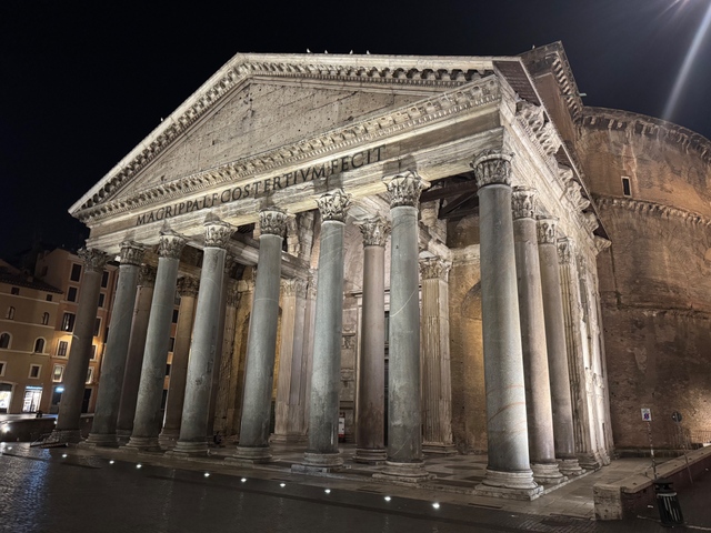 The illuminated facade and columned portico of the Pantheon in Rome at night.